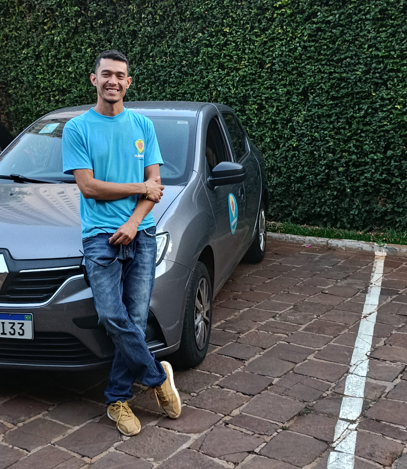 Flashdoguer sorrindo ao lado do carro adesivado